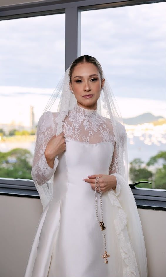 Noiva de véu e renda segurando um terço